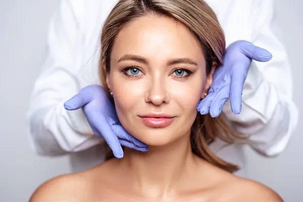 Close up of a woman's face with a doctor wearing rubber gloves standing behind her holding his hands around her face to show the amazing Botox Cosmetic treatment from Yashoda Singh, MD in Hamilton-Toronto-Niagara.