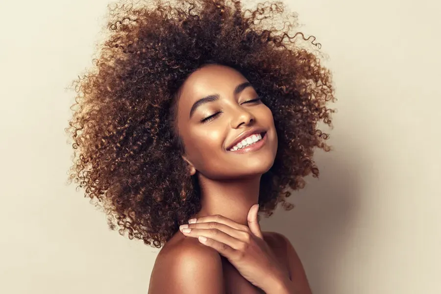 A black woman touches her beautiful smooth skin happily after receiving chemical peel treatments from Yashoda Singh, MD in Hamilton-Toronto-Niagara.