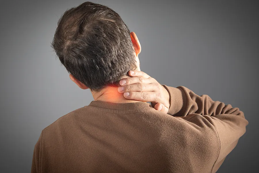 A man holds his neck in pain. Schedule chronic pain treatment from Yashoda Singh, MD in Hamilton-Toronto-Niagara.