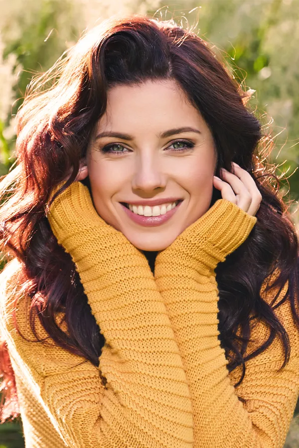 A beautiful woman in a yellow sweater. Get facial skin toning treatment from Yashoda Singh, MD in Hamilton-Toronto-Niagara.