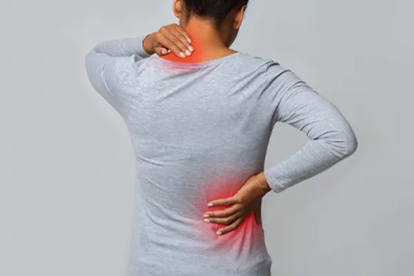 An image from behind of a woman suffering from Fibromyalgia holding her hands on her neck and lower back. Get fibromyalgia care from Yashoda Singh, MD in Hamilton-Toronto-Niagara.