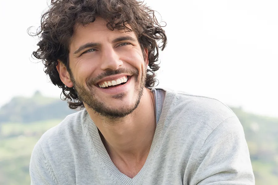 A man with a full head of curly brown hair. Schedule laser hair restoration treatment from Yashoda Singh, MD in Hamilton-Toronto-Niagara.