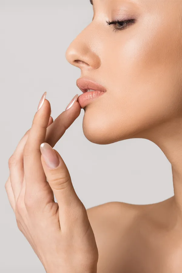 A beautiful woman touches her lips. Get lip enhancement treatment from Yashoda Singh, MD in Hamilton-Toronto-Niagara.