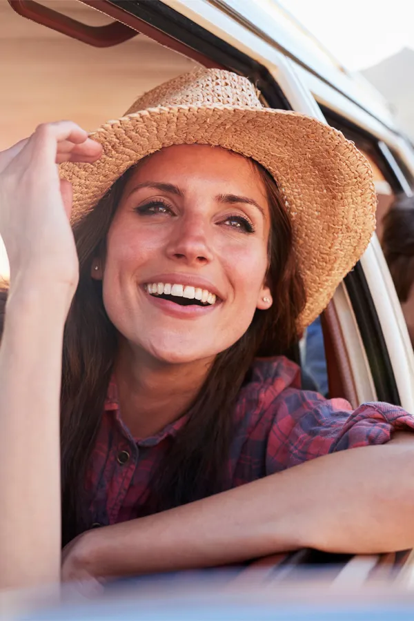A woman in a sunset leans out a car window smiling. Get radiofrequency microneedling with mesotherapy treatments from Yashoda Singh, MD in Hamilton-Toronto-Niagara.