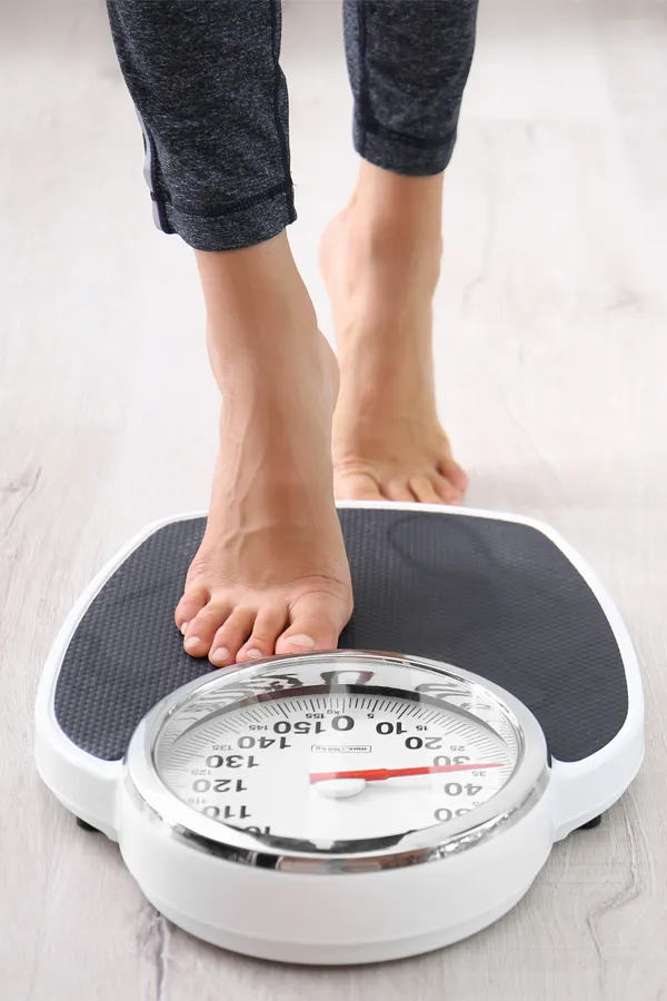 Close up of feet stepping onto a scale. Receive expert functional medicine for obesity treatment by Yashoda Singh, MD in Hamilton-Toronto-Niagara.