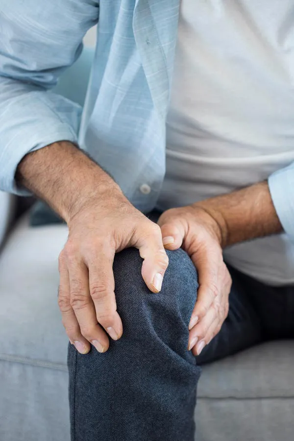 A close-up of a man holding his knee while experiencing pain from osteoporosis. Get osteoporosis treatment from Yashoda Singh, MD in Hamilton-Toronto-Niagara.