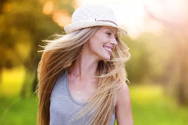 A woman shakes her long blonde hair. Get ultra-laser hair restoration from Yashoda Singh, MD in Hamilton-Toronto-Niagara.