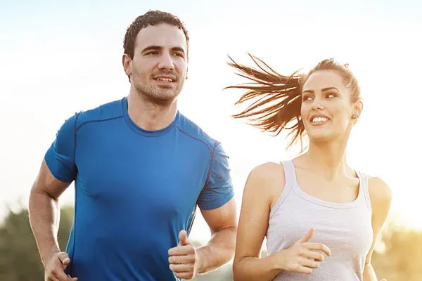 A couple happily jogging in the sunlight after receiving effective weight loss resistance care from Yashoda Singh, MD in Hamilton-Toronto-Niagara.
